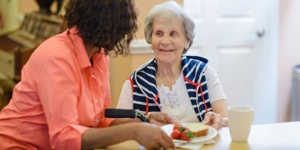Caregiver serves plate of food to client