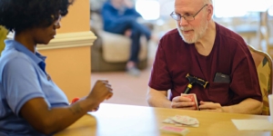 Caregiver and senior client play cards